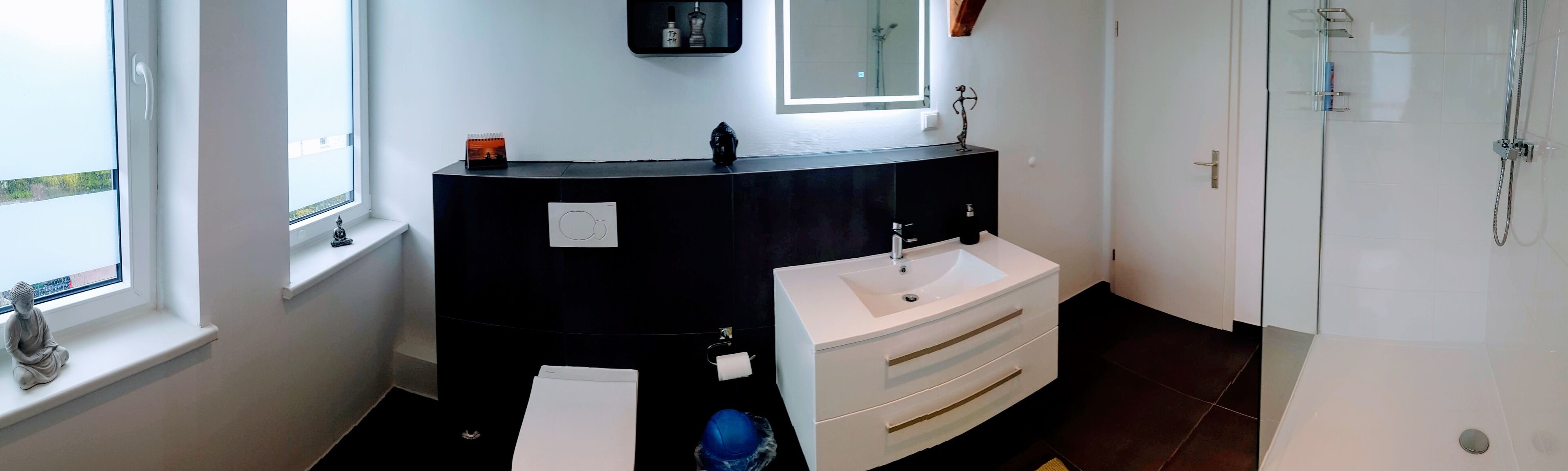 A bathroom with a black vanity, white sink, and a glass shower enclosure.