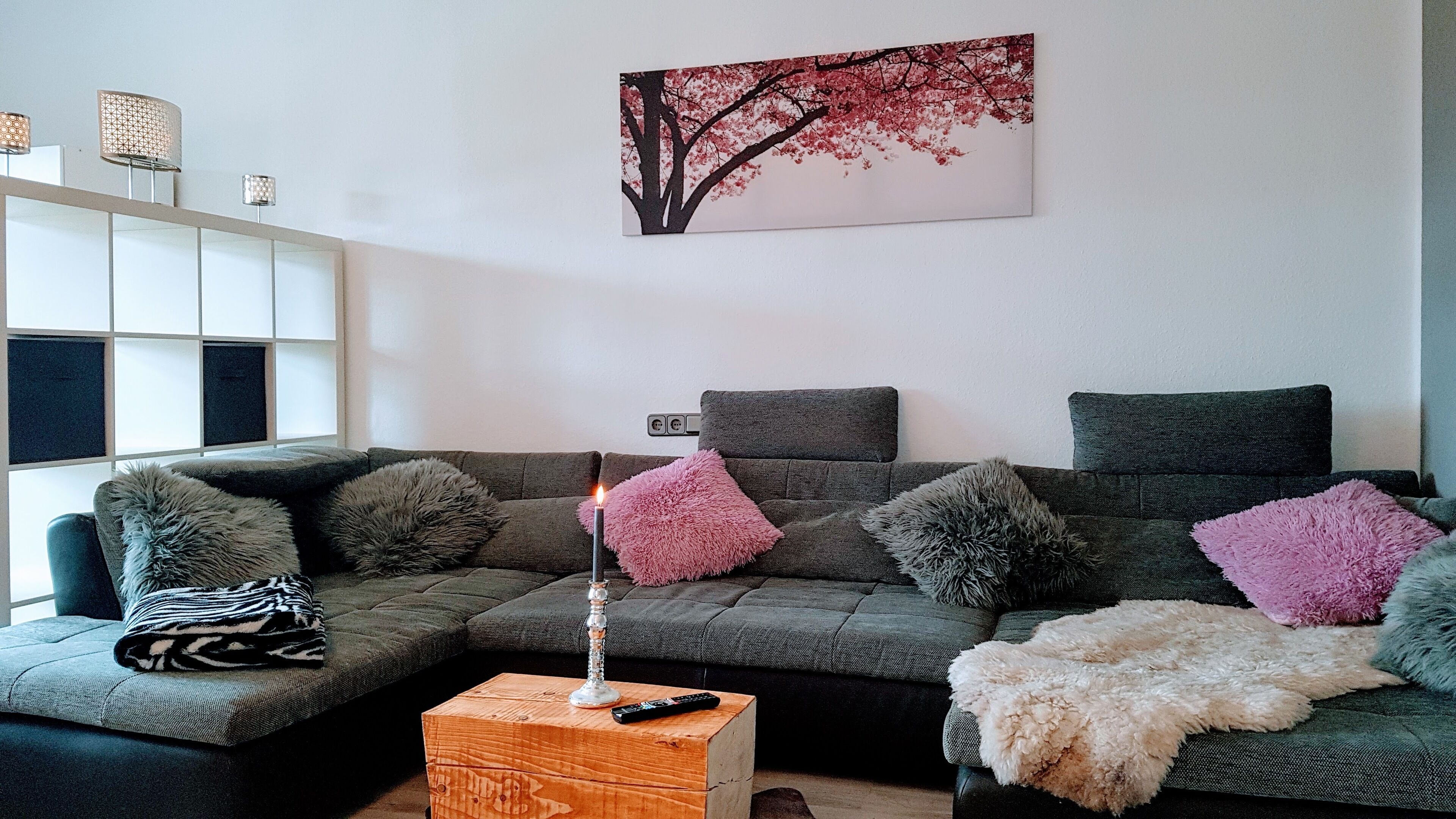 Un salon moderne avec un canapé d’angle, une petite table basse en bois et un tableau accroché au mur.