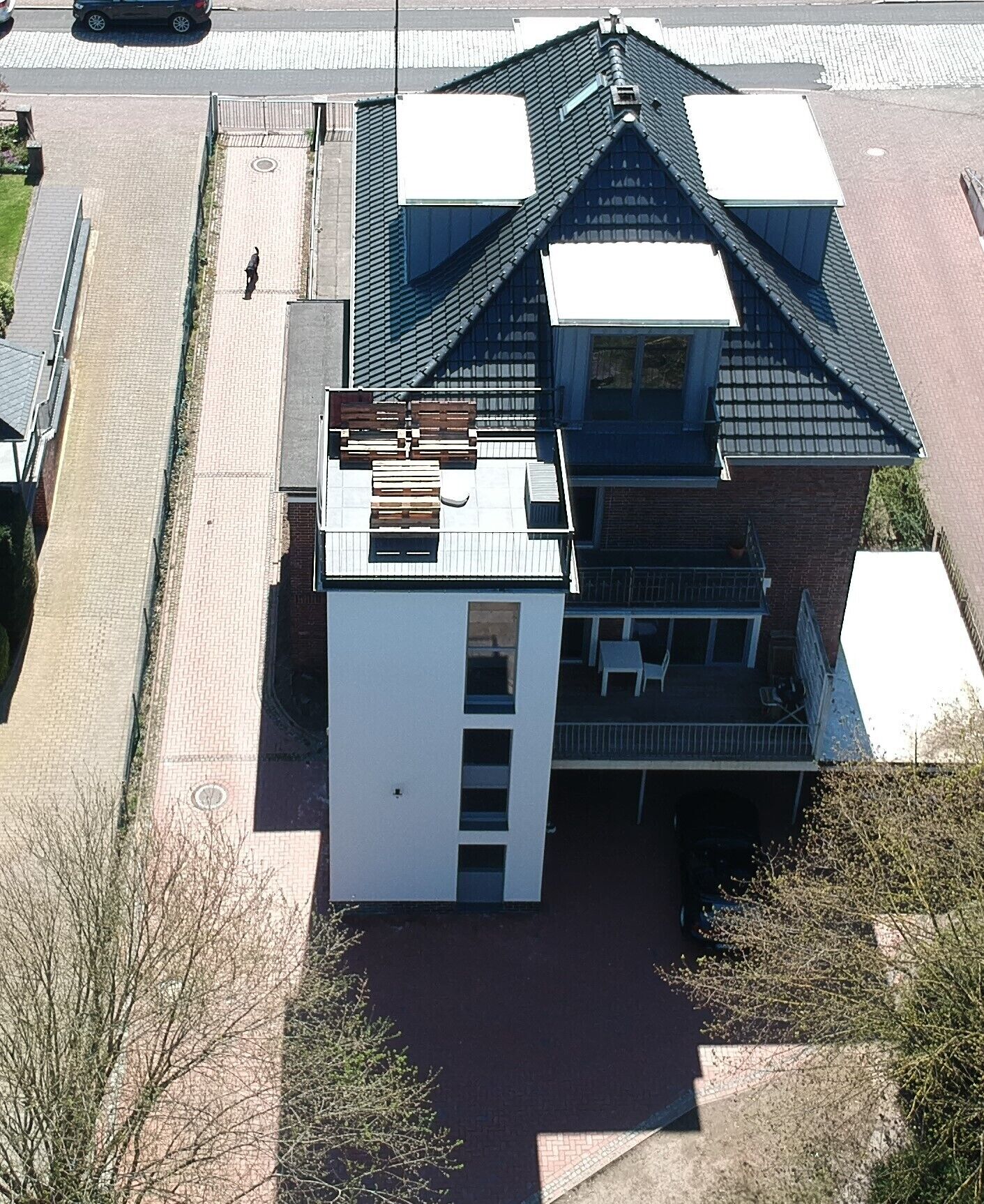 A two-story building with a flat roof, a small attached garage, and a visible balcony.