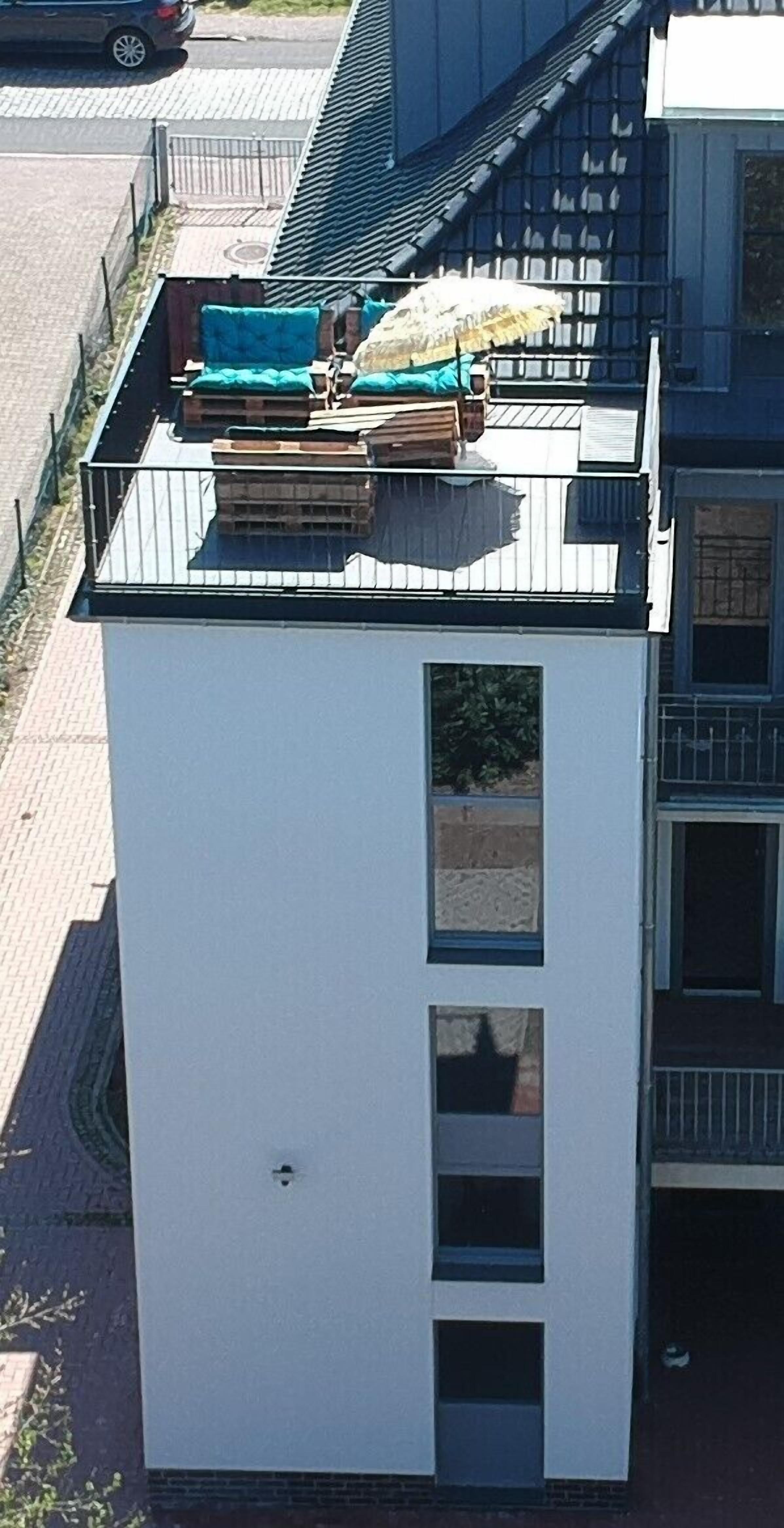 A modern building with a flat roof, a small balcony, and a window with a view of the street.