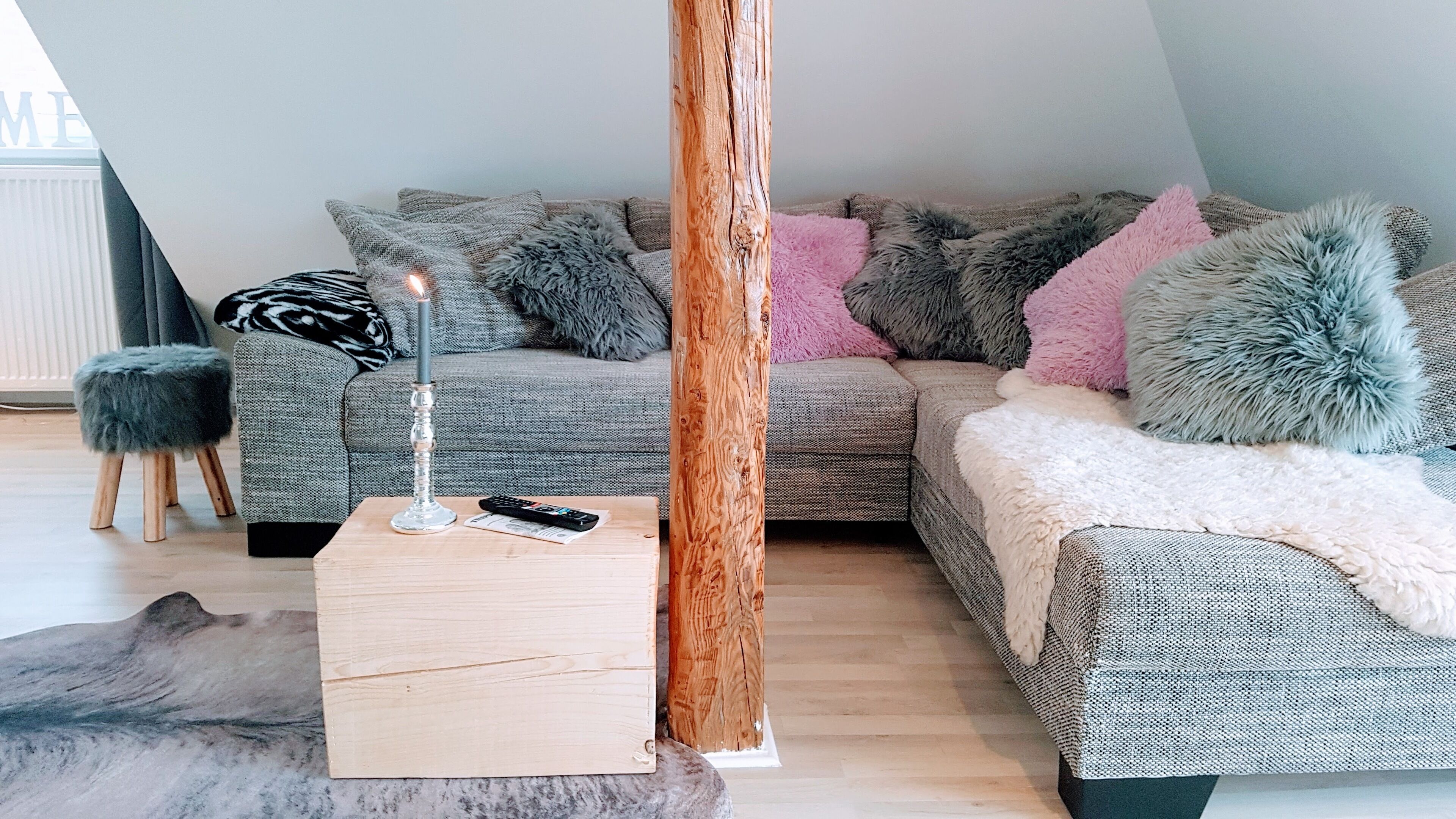 Una sala de estar moderna con un sofá gris, una mesa de centro de madera y un tapete gris suave.