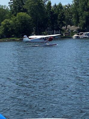 Ein See mit einem kleinen weißen Amphibienflugzeug und einem roten und weißen Amphibienflugzeug, das am Ufer liegt.