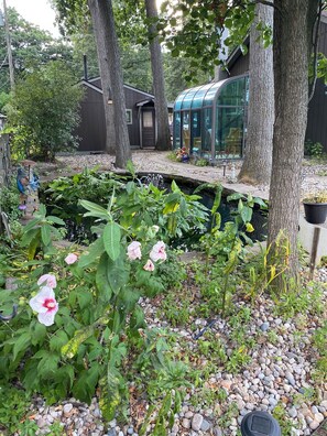 Un jardin avec un étang, des arbres et un bâtiment doté d’une façade en verre.