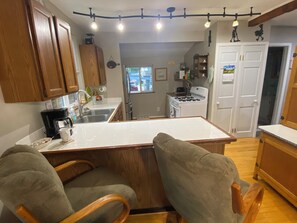 Une cuisine avec des meubles de rangement en bois, un plan de travail blanc et un îlot central doté de chaises.
