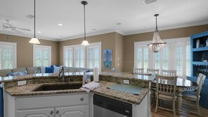 A spacious kitchen with granite countertops, a central island, and pendant lighting.