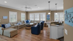 A spacious living room with a sofa set, a coffee table, and a kitchen area with a granite countertop and sink.