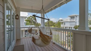 A porch with two hammocks, a white railing, and a view of neighboring houses.