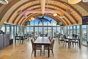 Enjoy panoramic views of the marina and cityscape from this dining area with a high ceiling and large windows.