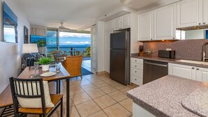 A modern kitchen with white cabinets, a stainless steel refrigerator, and a granite countertop. - Mana Kai 2BR across Kamaole III Beach, ocean views, summer deal (Kihei)