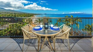 A round table with two chairs and a view of a beach and ocean. - Mana Kai 2BR across Kamaole III Beach, ocean views, summer deal (Kihei)