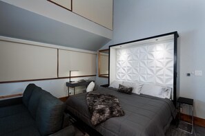 A modern bedroom with a large bed, a nightstand, a desk, and a sofa. - Sunshine Suite | AC, Pool, Hot Tub, Golf & Ski (Durango)