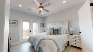 Ein Schlafzimmer mit Bett, Nachttischen, Deckenventilator und einer Tür.