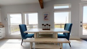 Ein Essbereich mit Tisch und Stühlen, großen Fenstern, einer Uhr und einem Gemälde.
