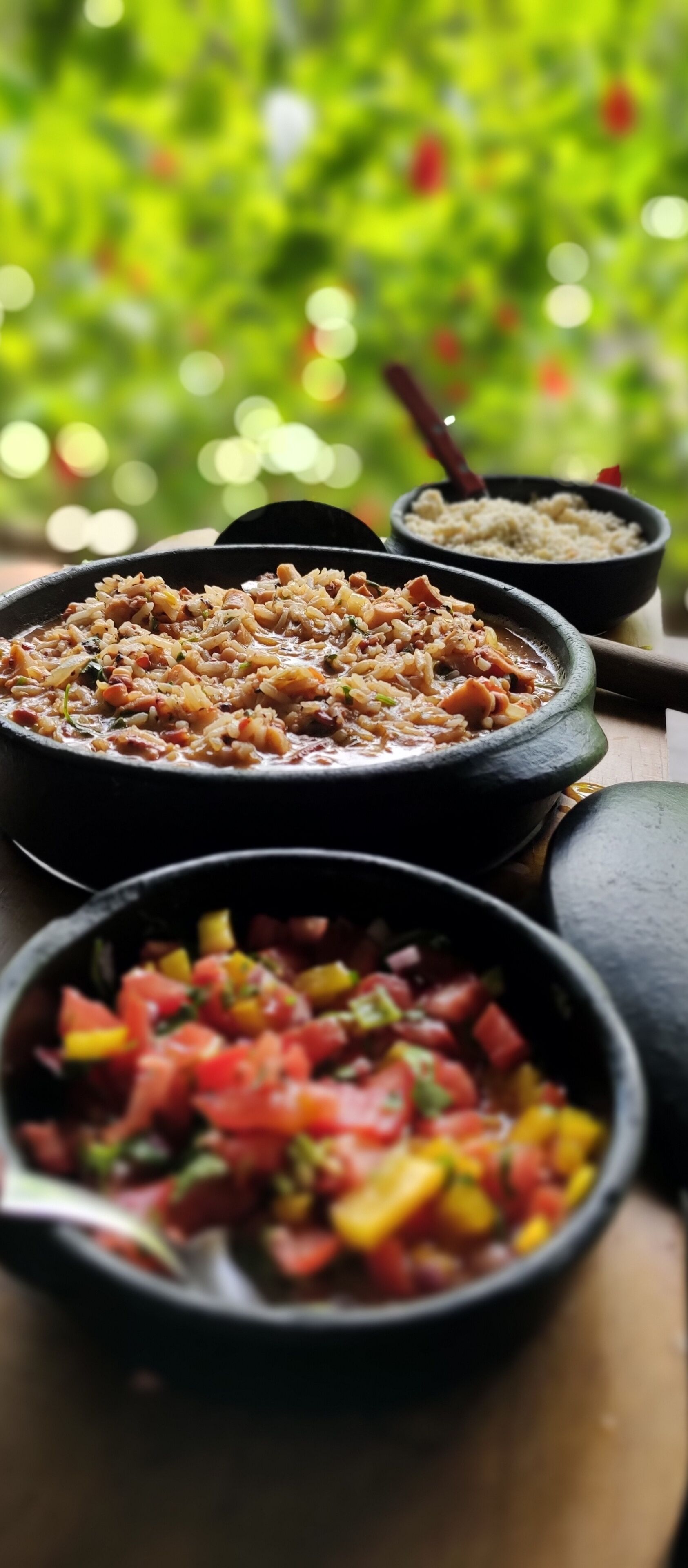 A variety of dishes in black bowls on a wooden table.