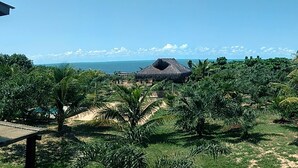 Ein tropisches Resort mit einem Gebäude mit Reetdach, Palmen und Blick auf den Ozean.