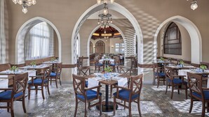 A spacious dining area with multiple tables and chairs, arched ceilings, and hanging chandeliers. - Jaz Makadi Gardens - TUI BLUE Makadi Gardens - Adults Friendly 16 Years Plus (Makadi Bay)