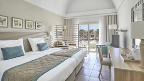 A hotel room with a large bed, a desk, and a balcony with a view. - Jaz Makadi Gardens - TUI BLUE Makadi Gardens - Adults Friendly 16 Years Plus (Makadi Bay)