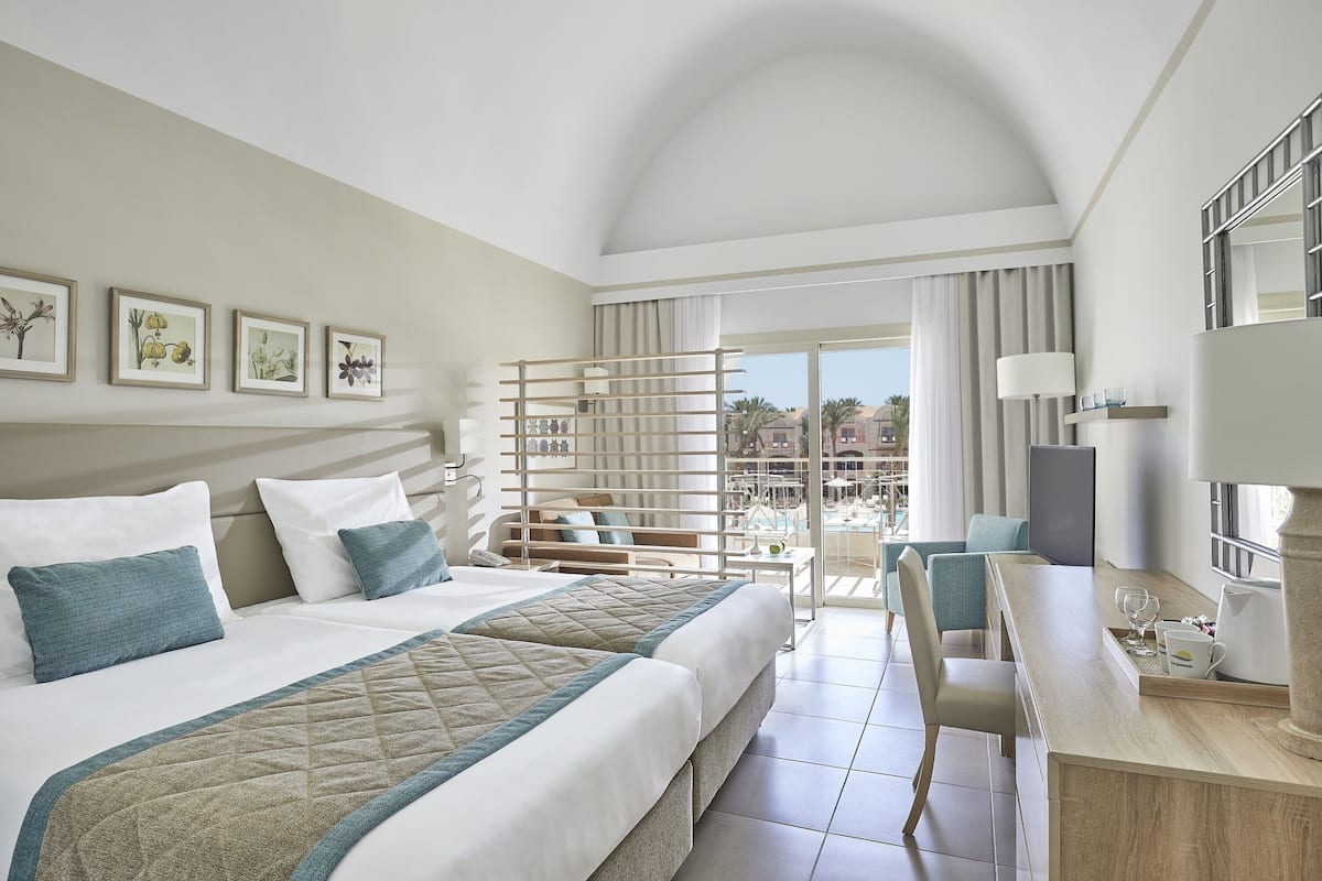 Ein Hotelzimmer mit einem großen Bett, einem Schreibtisch und einem Balkon mit Blick.