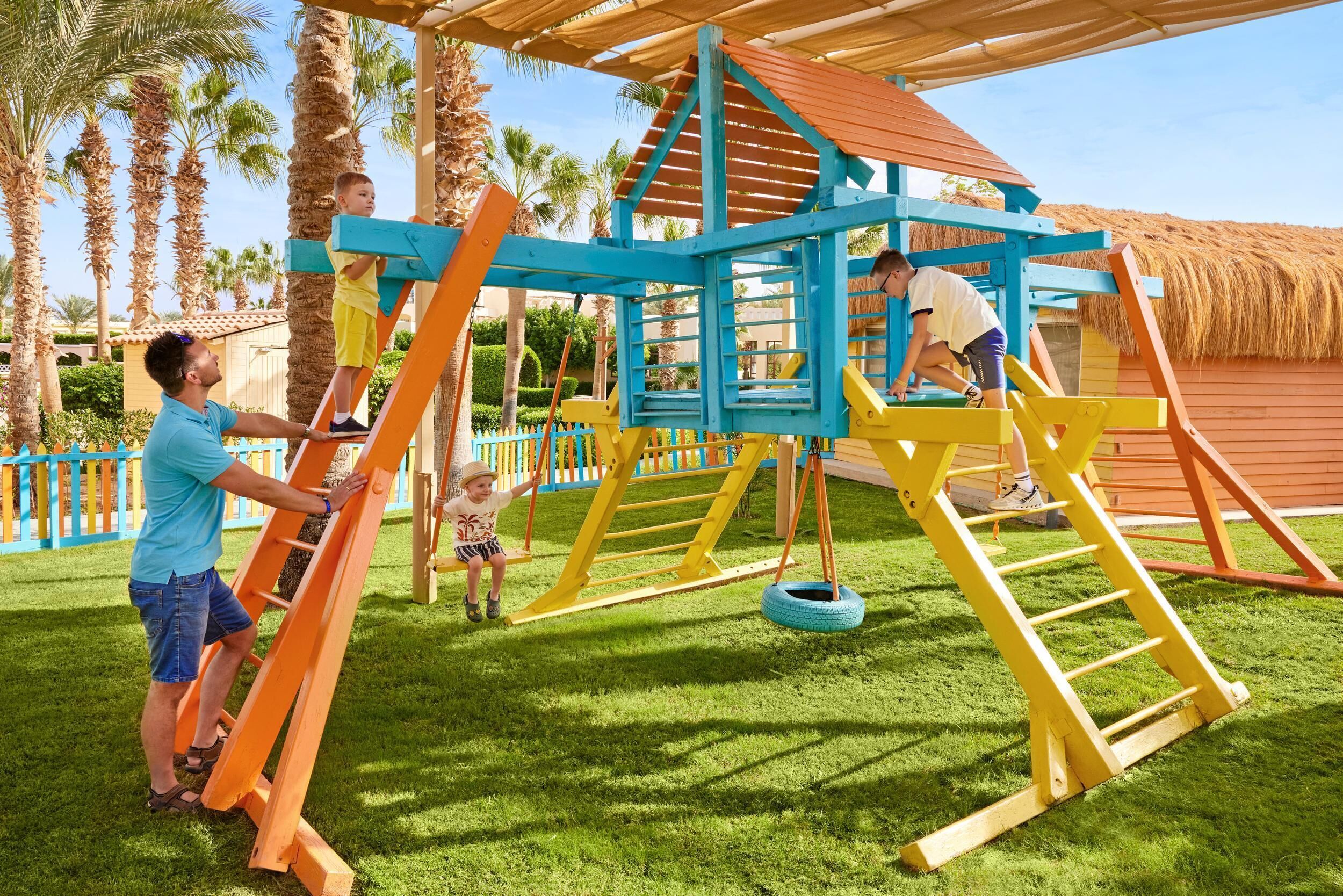 Une aire de jeux avec une structure d’escalade, une balançoire et une balançoire en forme de pneu.