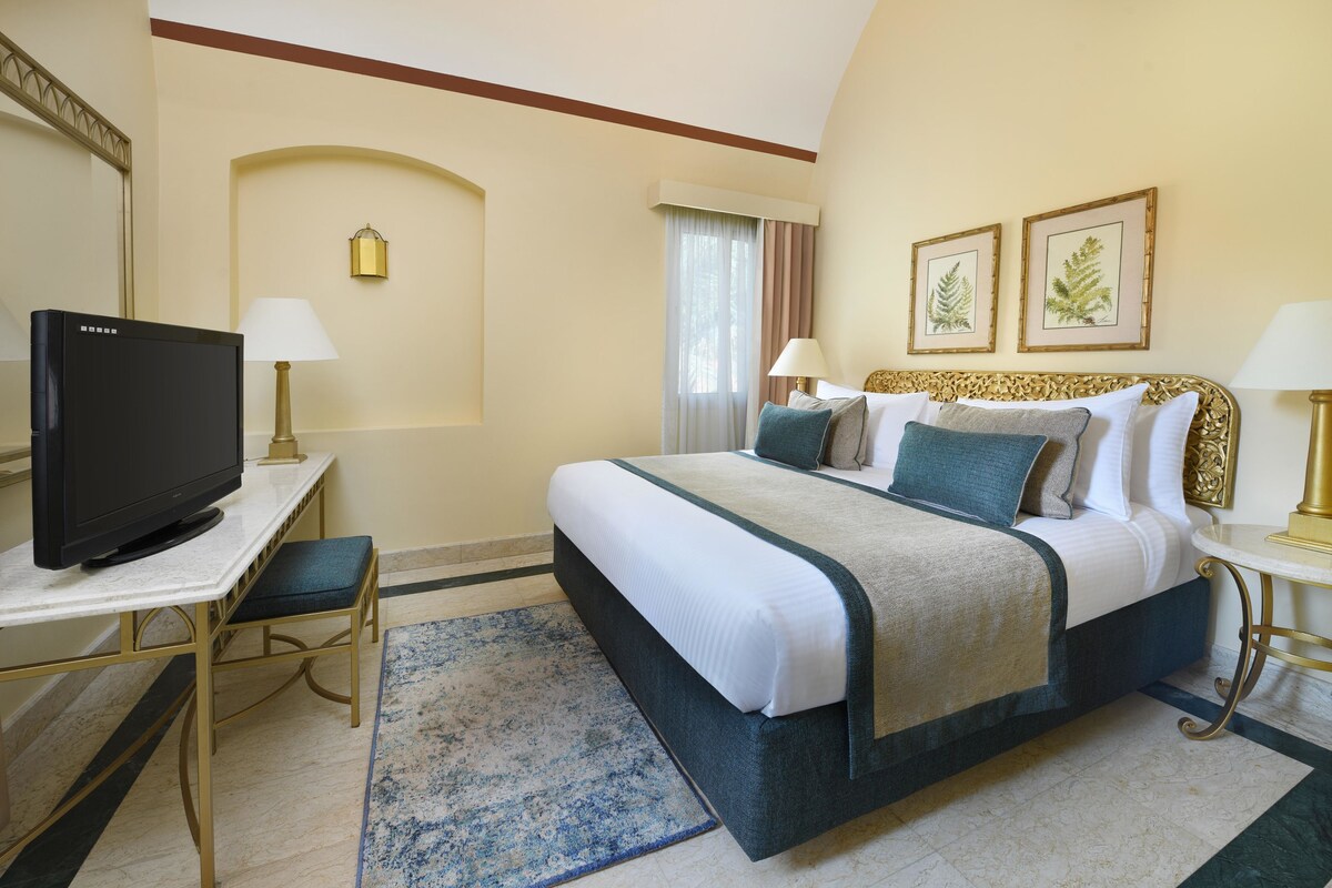 A hotel room with a bed, a television, a desk, and a chair.