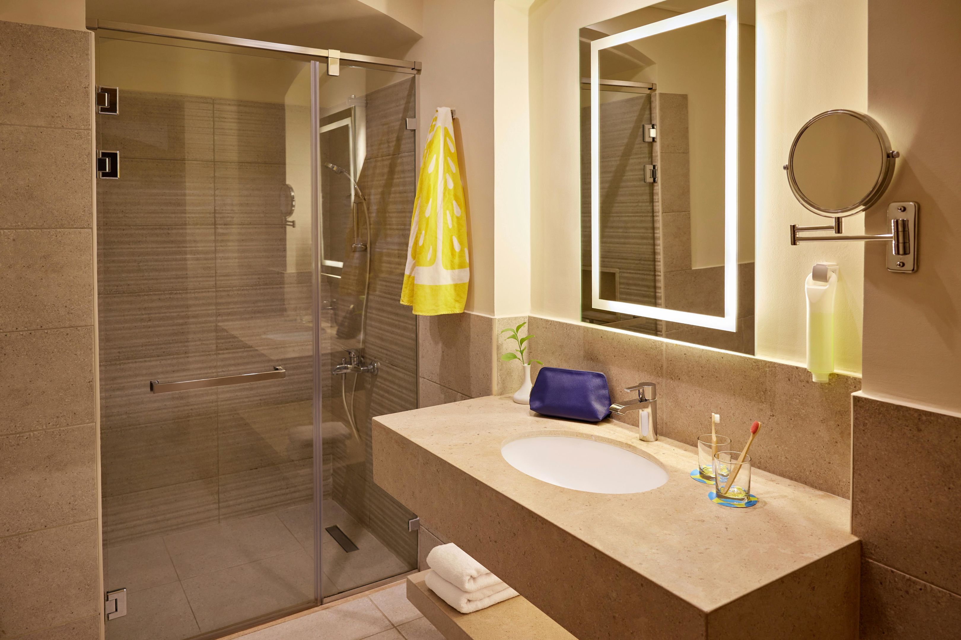 A modern bathroom with a glass shower enclosure, a beige sink, a mirror, and a towel rack.