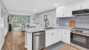 A modern kitchen with white cabinets, stainless steel appliances, and a large island. - TB 9G Great dog friendly 2 bedroom condo on the golf course at True Blue 9G (Pawleys Island)