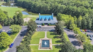 A large building with a blue roof, surrounded by a well-maintained lawn and a pond. - TB 9G Great dog friendly 2 bedroom condo on the golf course at True Blue 9G (Pawleys Island)