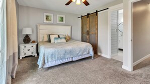 A bedroom with a bed, a nightstand, a lamp, a ceiling fan, and a sliding door closet. - Emerald Escapes unit 41 (Miramar Beach)