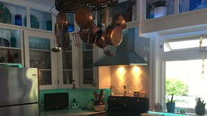 A kitchen with a wooden table, stainless steel refrigerator, and copper cookware hanging above.