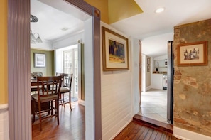 A hallway with wooden flooring, a dining area with a table and chairs, and a kitchen visible in the background. - York Street Gem - A Taste of 1800s Savannah (Savannah)
