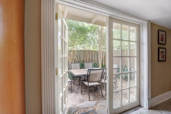 A patio area with a table and chairs, a wooden door leading outside, and a tiled floor. - York Street Gem - A Taste of 1800s Savannah (Savannah)