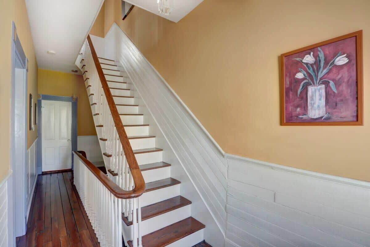 Un escalier avec des rampes blanches et des marches en bois menant à une porte.