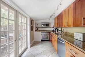 A kitchen with wooden cabinets, a microwave, an oven, and a dishwasher. - York Street Gem - A Taste of 1800s Savannah (Savannah)