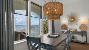 A dining area with a view of the sea, a woven pendant light, and decorative wall art. - 🌅 Let's Do Sunset - Dock, Gulf Access, Sunset Deck + Pet Friendly 🐾 (Pensacola Beach)