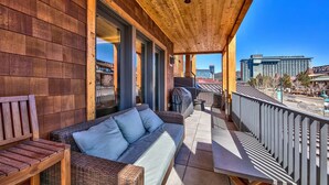 Ein Holzbalkon mit einer Couch und einem Tisch, mit Blick auf eine Stadtlandschaft.