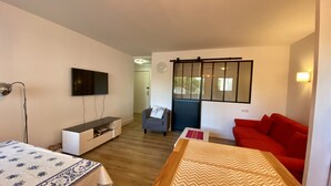 Un salon moderne avec un téléviseur à écran plat, un canapé, un fauteuil et une table en bois.