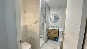 Une salle de bain moderne équipée de toilettes, d’une douche et d’un lavabo.