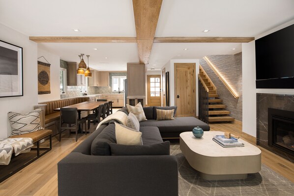 A modern living room with a large sectional sofa, a dining area, and a kitchen in the background. - Vail Trails East #10a 3 Bedroom Condo by RedAwning (Vail)