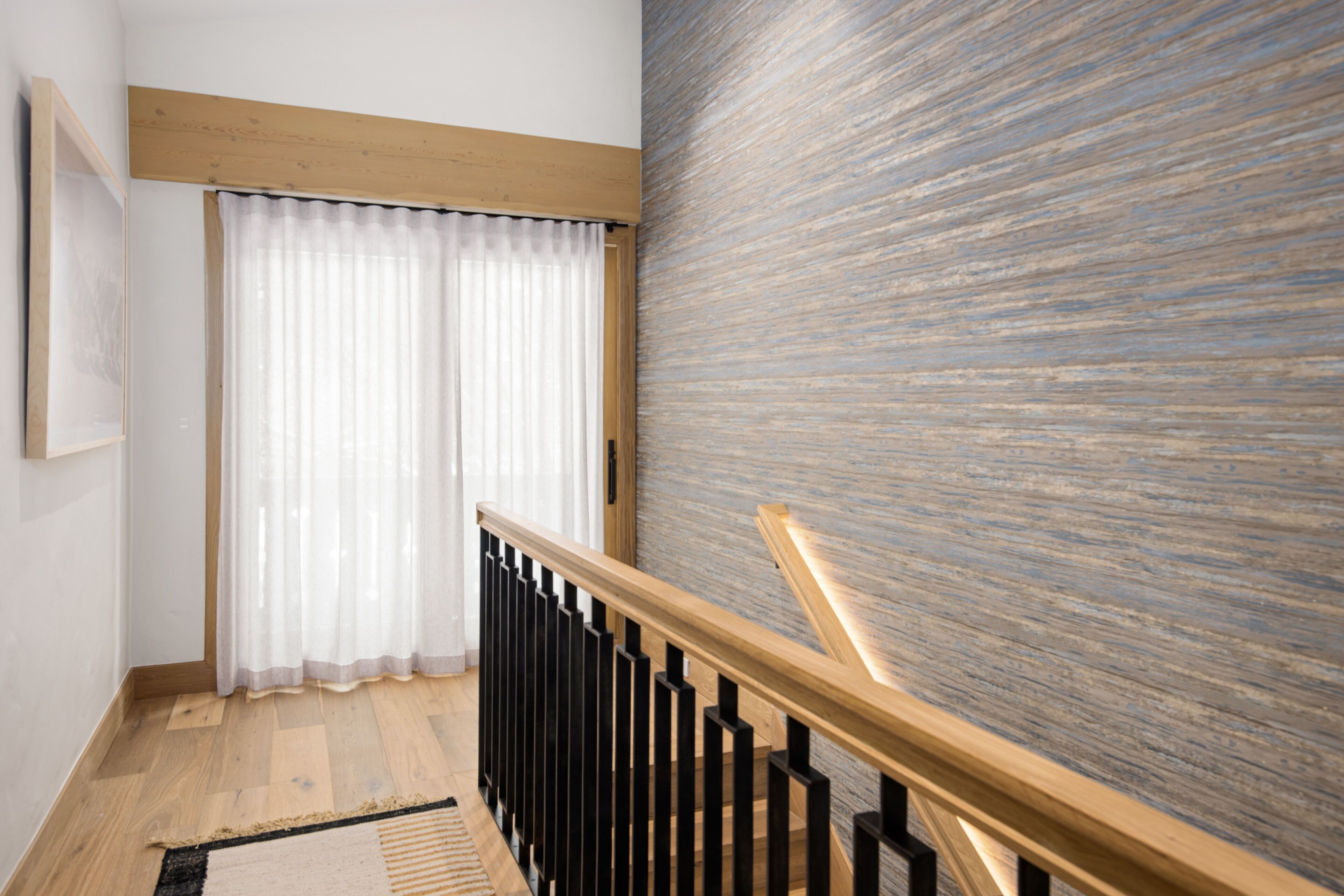 A staircase with wooden railings and a textured wall.