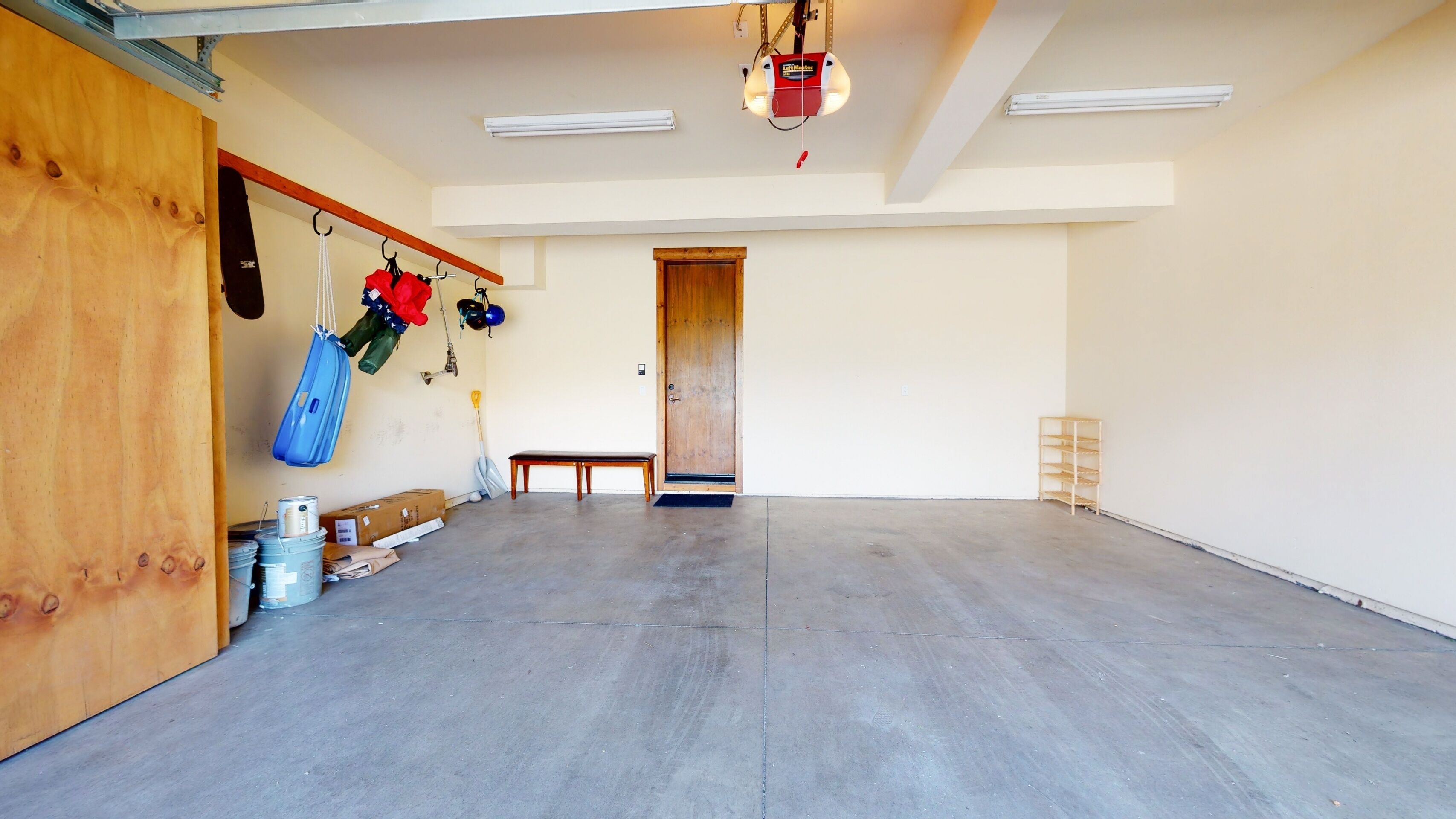 Una habitación amplia con suelo de concreto, una puerta de madera y un banco.