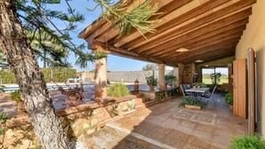 An outdoor patio area with a wooden pergola, stone flooring, and potted plants. - Hort de Sa Barrala, a small finca near Ses Covetes - Es Trenc beach (Ses Salines)