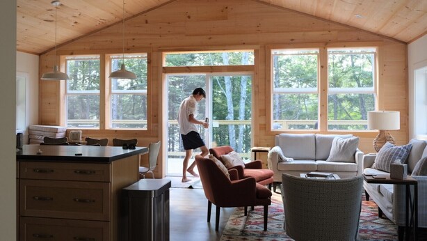A spacious cabin interior with a high ceiling, large windows, a dining area, and a cozy living space with a sofa and armchairs. - New Waterfront Lake House - completed 2021 (Belgrade)