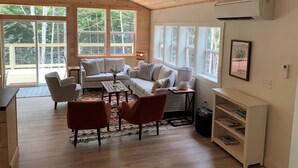 A cozy room with a wooden ceiling, large windows, a sofa set, a coffee table, and a bookshelf. - New Waterfront Lake House - completed 2021 (Belgrade)