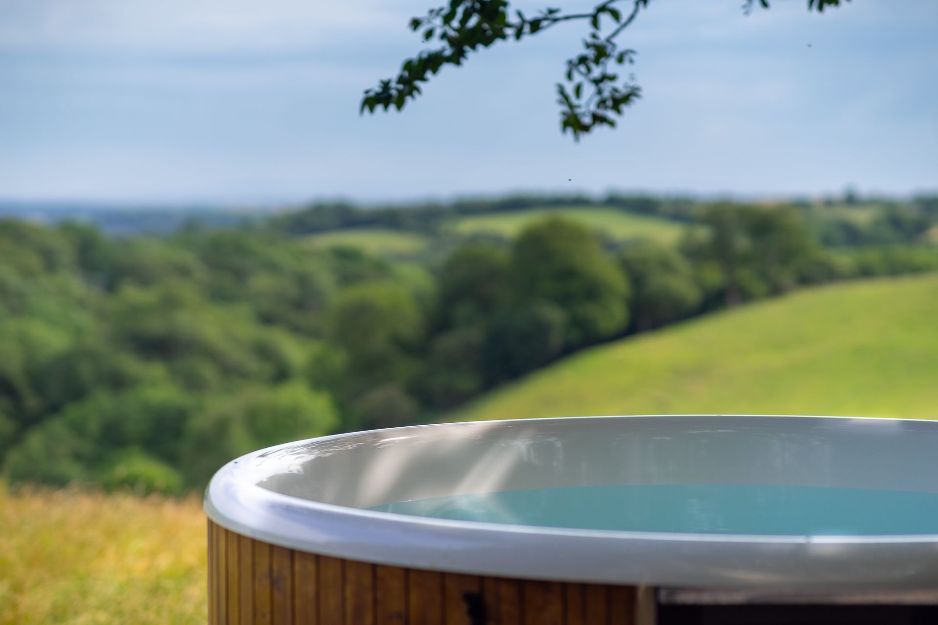 A hot tub with a view of a green landscape and hills in the background.