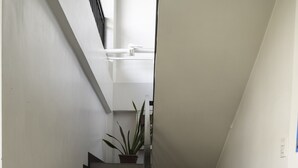 A staircase with a handrail, a potted plant at the top, and a door at the bottom. - OYO 711 Goff's Place (Cagayan de Oro)