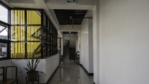 A hallway with a staircase, a potted plant, and a bench. - OYO 711 Goff's Place (Cagayan de Oro)