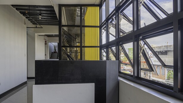 A modern interior with a staircase, large windows, and a view of the city. - OYO 711 Goff's Place (Cagayan de Oro)