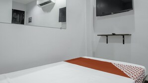 A hotel room with a bed, a TV mounted on the wall, a mirror, and an air conditioning unit. - OYO 711 Goff's Place (Cagayan de Oro)