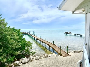 A wooden pier extending into calm waters, surrounded by rocks and greenery.