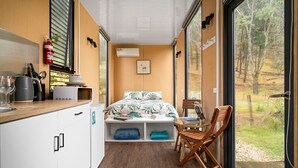 Habitación pequeña con cama, una mesita y ventana con vistas a un paisaje natural.